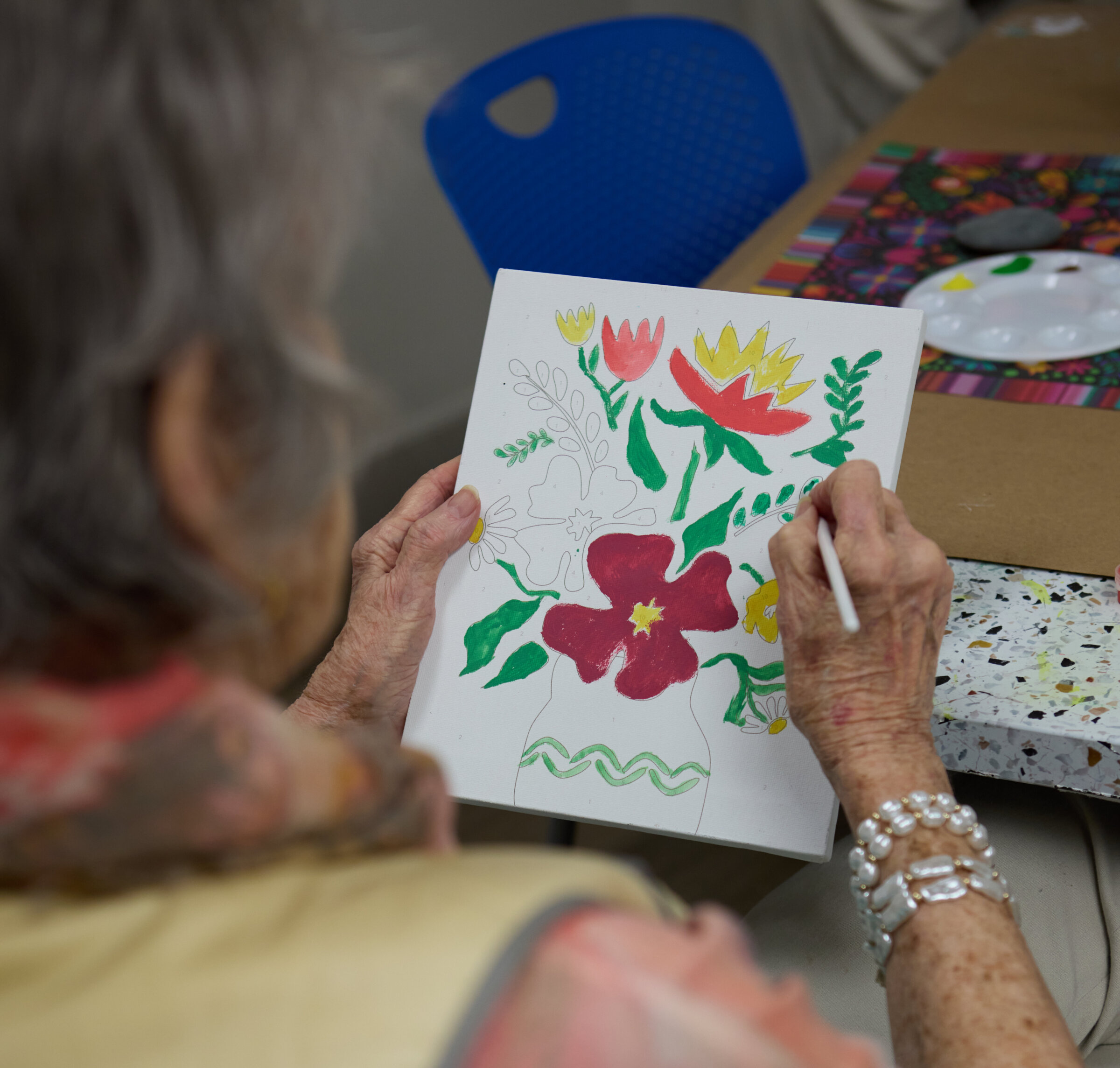 A senior woman paints while participating in activities of daily life at Village at The Triangle